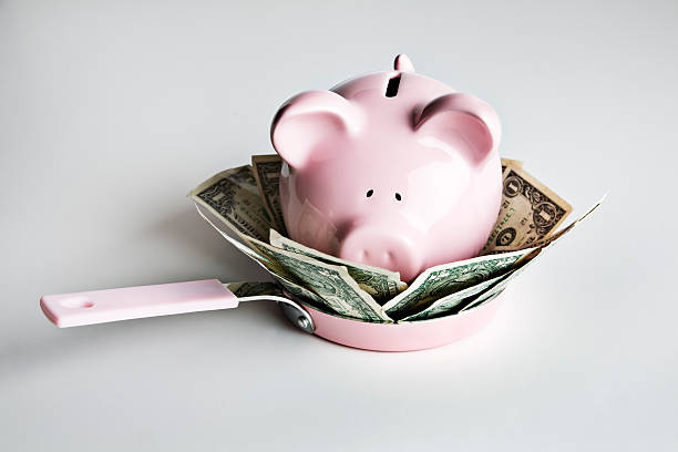 Piggy bank and money in frying pan stock photo