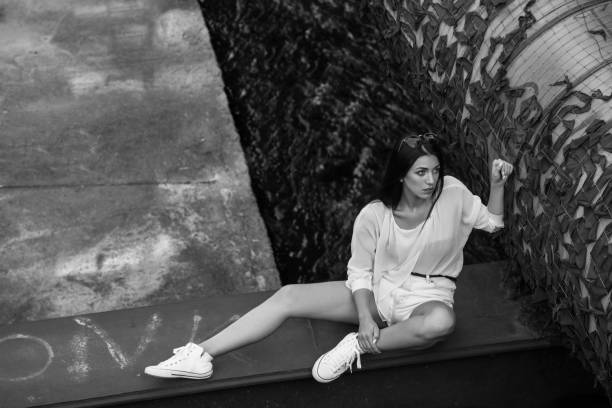 istock attractive woman in white clothes posing while sitting at abandoned building 955672466