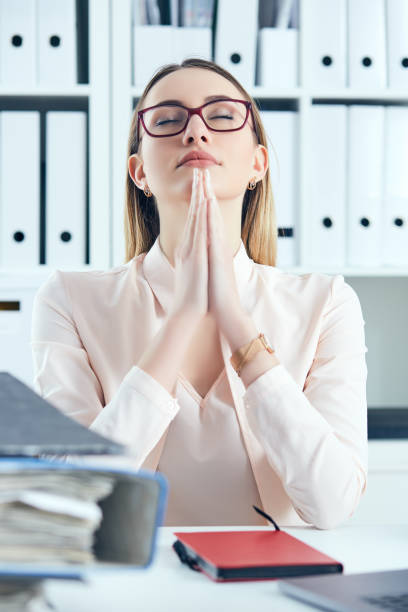 istock Close up stressed office woman doing praying hand gesture while looking at the pile of documents at her workplace 955675452