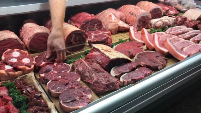 Food preparation in traditional UK Butchers shop display counter time lapse.