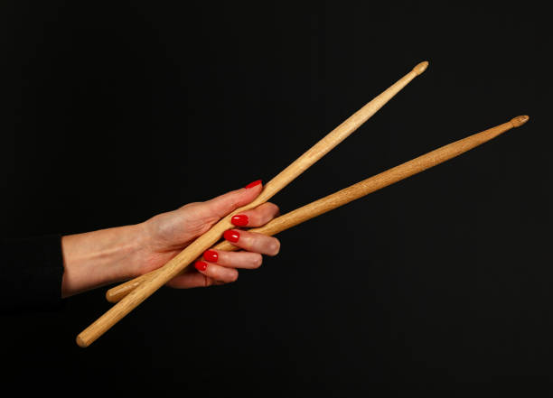 Close up woman hand with drumsticks over black Close up woman hand with red nails holding two drumsticks over black background, side view rocker nails stock pictures, royalty-free photos & images