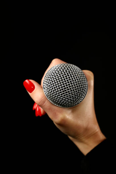 Woman hand with microphone isolated on black Woman hand with red nails holding microphone isolated on black background rocker nails stock pictures, royalty-free photos & images