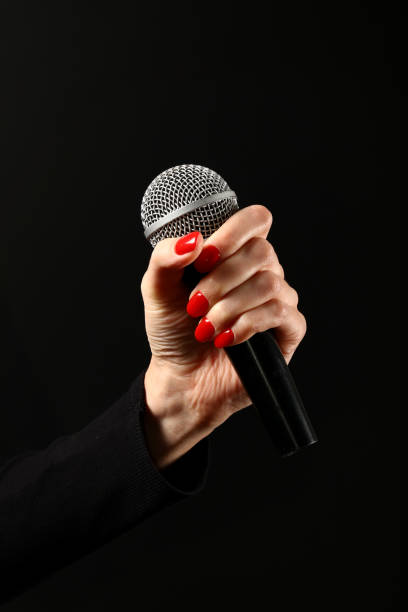 Woman hand with microphone isolated on black Woman hand with red nails holding microphone isolated on black background rocker nails stock pictures, royalty-free photos & images