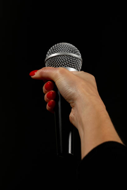 Woman hand with microphone isolated on black Woman hand with red nails holding microphone isolated on black background rocker nails stock pictures, royalty-free photos & images