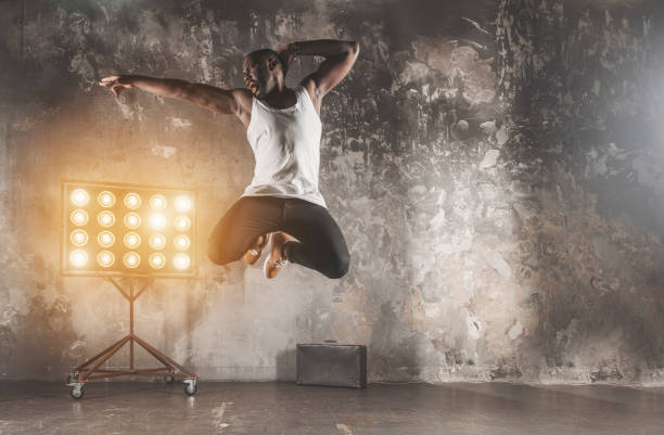 istock a young black man jumping while dancing  in front of a rustic wall background 955690606