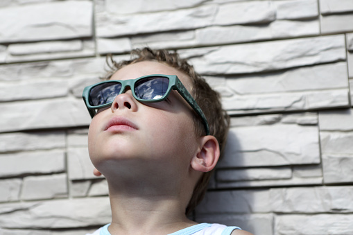 Kid with sunglasses on a wall background