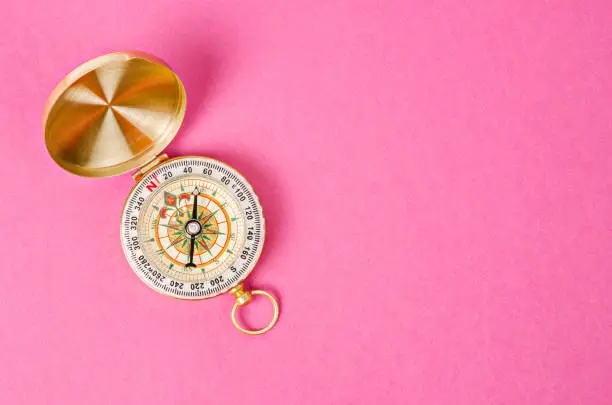 Photo of Vintage gold compass on pink background