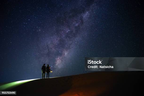 Two Travellers Look At The Milky Way On Starry Night On Sand Dunes Hill Stock Photo - Download Image Now