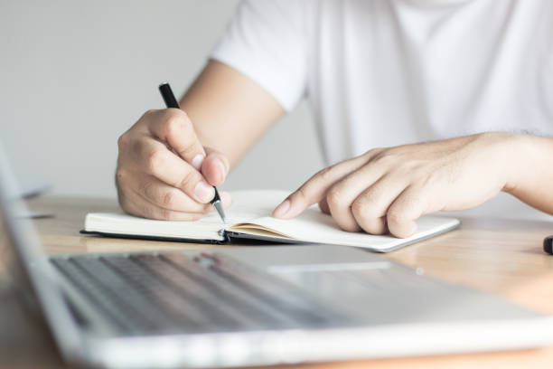 istock writing, knowledge and learning concept, hand of man recording information on notebook 955703596