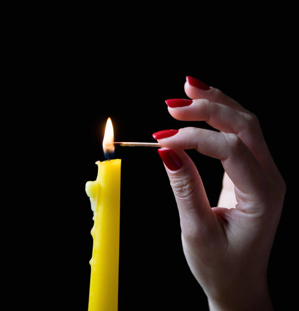 istock A graceful female hand with a beautiful manicure lights a candle. 955703888