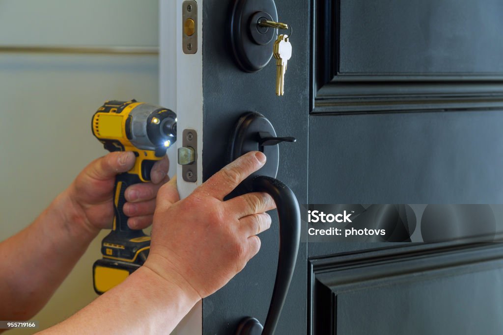 house exterior door with the inside internal parts of the lock visible of a professional locksmith installing or repairing a new deadbolt lock Closeup of a professional locksmith installing a new lock on a house exterior door with the inside internal parts of the lock Locksmith Stock Photo