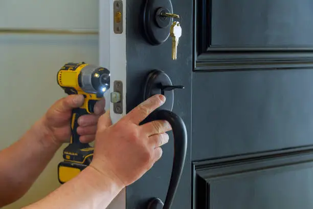 Closeup of a professional locksmith installing a new lock on a house exterior door with the inside internal parts of the lock