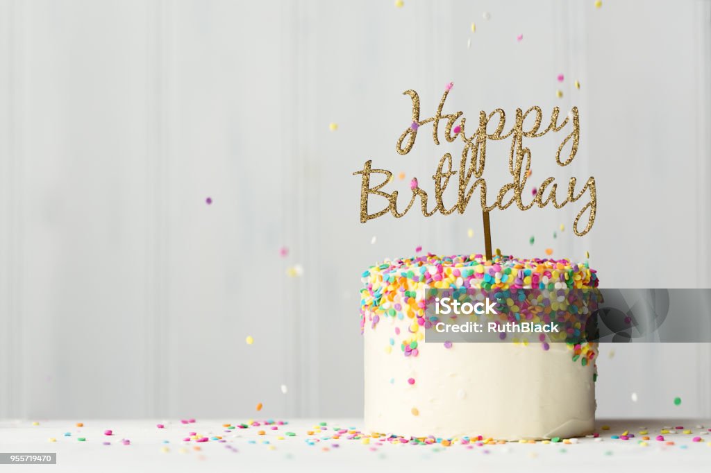 Birthday cake with gold banner Colorful birthday cake with golden happy birthday banner and falling sprinkles Birthday Stock Photo