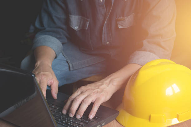 istock Architect engineer using laptop for working with yellow helmet and laptop on table. 955724346