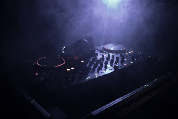 istock DJ Spinning, Mixing, and Scratching in a Night Club, Hands of dj tweak various track controls on dj's deck, strobe lights and fog, or Dj mixes the track in the nightclub at party 955729306