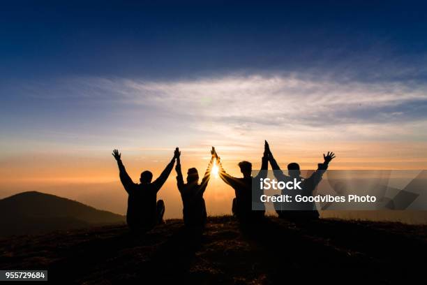 Silhouette Of Friends Shake Hands Up And Sitting Together In Sunset For Happinessbusiness Successful And Team Work Concept Stock Photo - Download Image Now