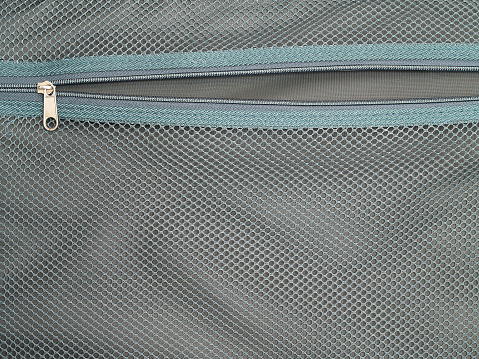 open zipper inside suitcase with green mesh texture background, empty storage compartment in bag