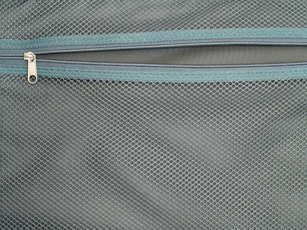 open zipper inside suitcase with green mesh texture background, empty storage compartment in bag
