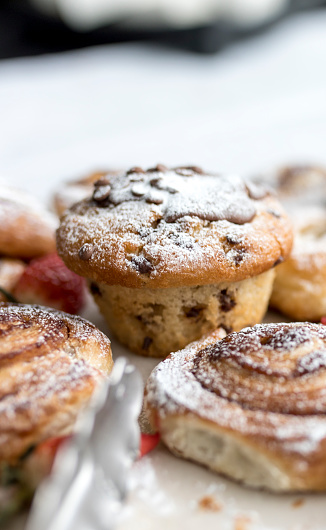 A delicious, freshly baked chocolate chip muffin and pastries frosted or spinkled with icing sugar on a business breakfast buffet in the UK