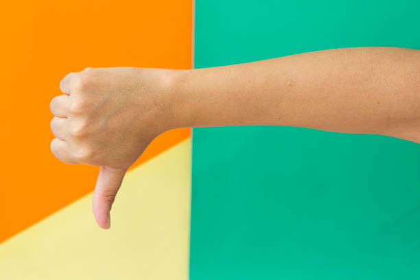 istock Women showing thumbs down on multi colored background 955749246