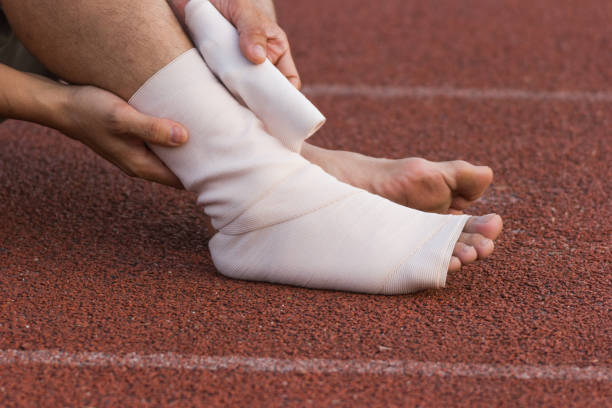 istock Male athlete applying compression bandage onto ankle injury 955755748