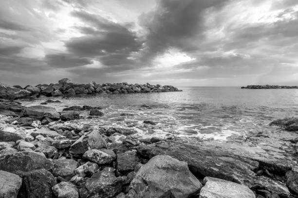 istock Black and white seascape with rocks on the beach. 955757342