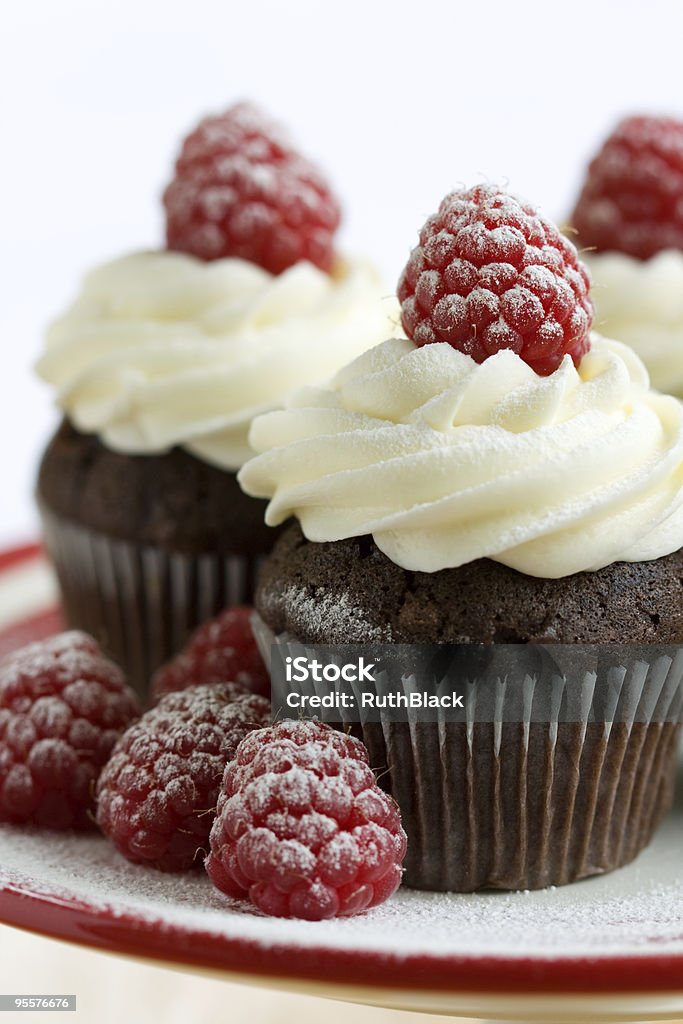 Chocolate and raspberry cupcakes served on a plate Chocolate cupcakes decorated with fresh cream and raspberries Cupcake Stock Photo