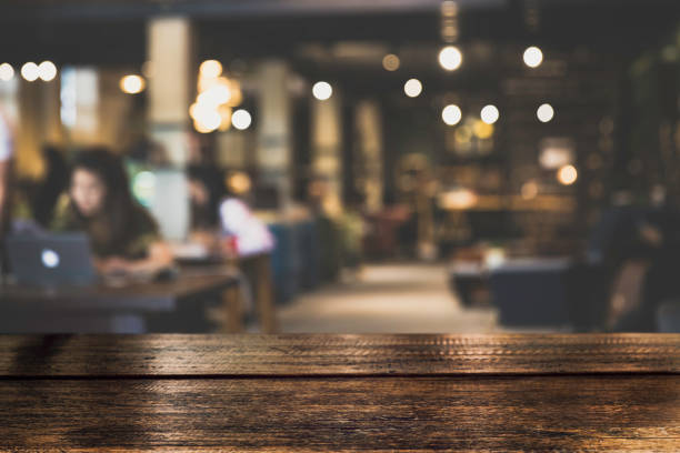 istock Dark Table top Counter with blurred of coffee shop or modern library . Abstract, freelancer working on laptop. 955768734