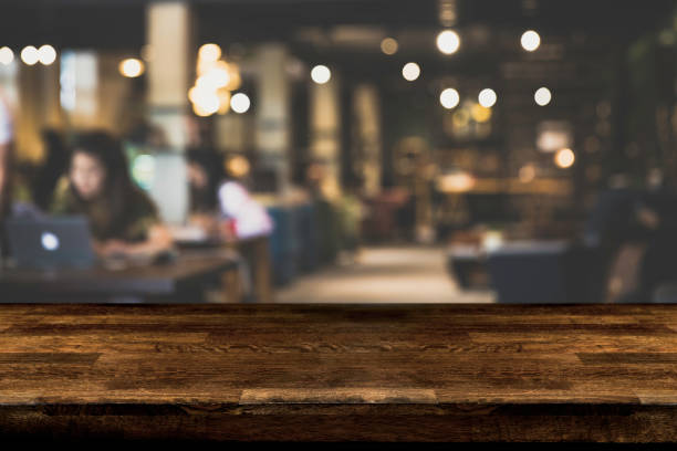 istock Dark Table top Counter with blurred of coffee shop or modern library . Abstract, freelancer working on laptop. 955768776