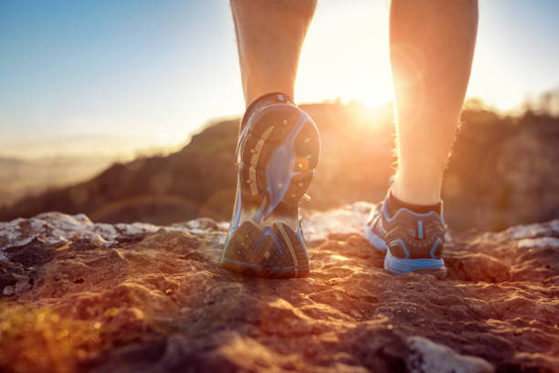 istock Runner feet running on trail looking at sunset 955771328