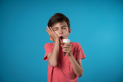 Worried boy experiencing tooth ache over colored background