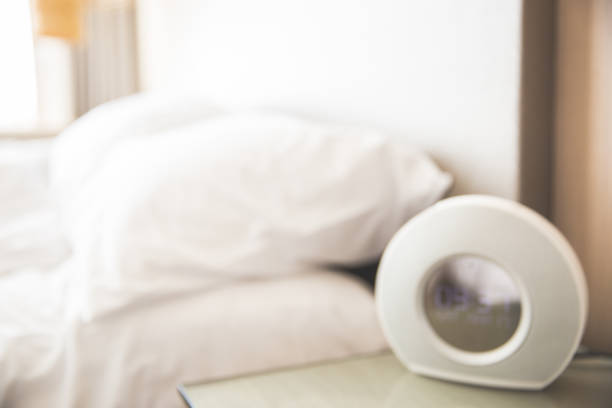 istock Hotel room alarm clock on modern glass table beside the bed. 955772236