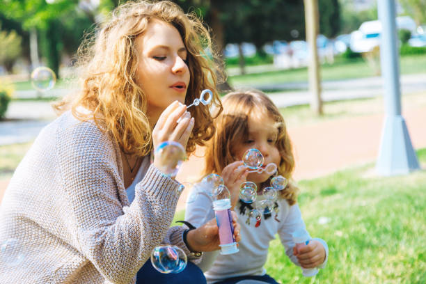 istock Happy family playing soap bubbles in park. 955772502