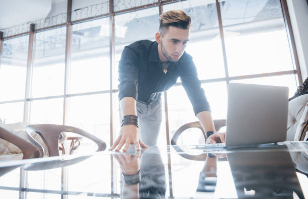 istock Conceived young man working on laptop while sitting at his working place in office 955772542