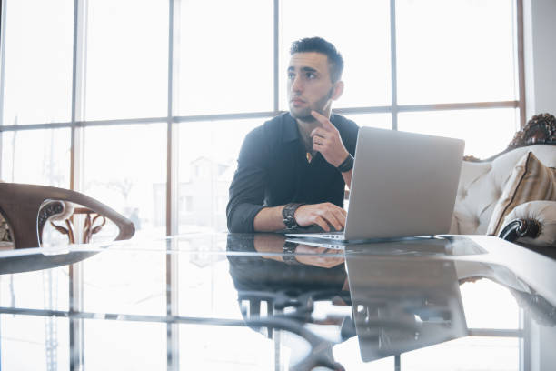 istock Conceived young man working on laptop while sitting at his working place in office 955772566