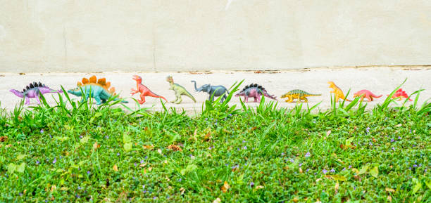 A colorful Group of toy dinosaurs Walking Across A Sidewalk
