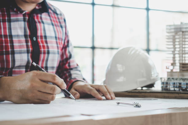 istock Construction concept, Hands of architect or engineer working for new project plan on blueprint, model building and engineering tools in working site 955777454