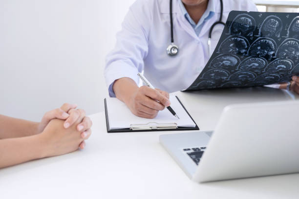 istock Professor Doctor report and recommend a method with patient treatment, results on brain x-ray film About the problem of the patient 955777464