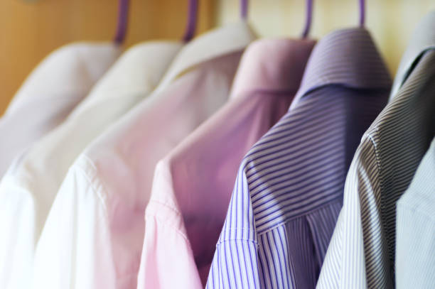 istock Different colored men's shirts hanging on hangers in wardrobe 955777910