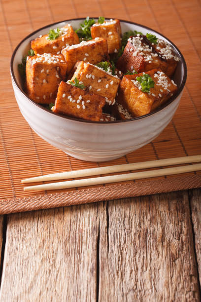istock Stir Fry dish: tofu cheese with sesame seeds  in a bowl close-up. vertical 955788544