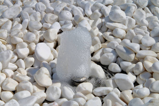 istock Small fountain making its way through a white pebble. 955791682