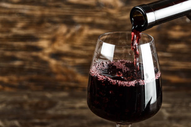 istock red wine pour into a glass on a wooden background 955791684