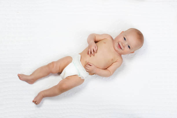 Little boy in diaper lying on white bed