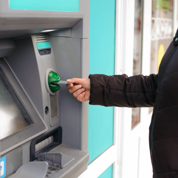 istock Hand inserting ATM card into bank machine to withdraw money 955795838