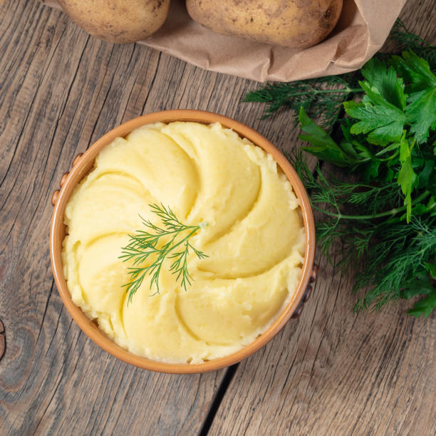 istock Mashed potatoes, boiled puree in brown bowl on dark wooden rustic background, top view 955799740