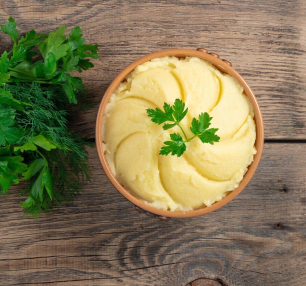 istock Mashed potatoes, boiled puree in brown bowl on dark wooden rustic background, top view 955799934