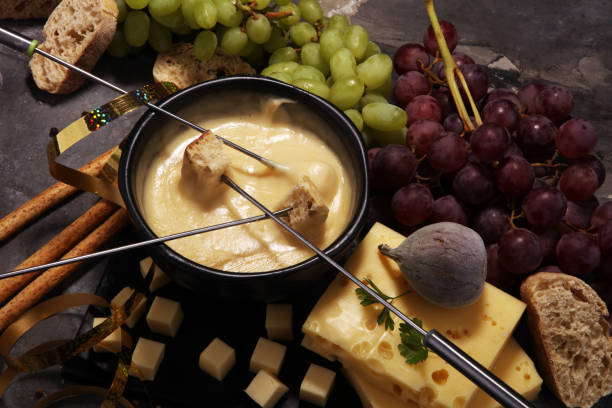 istock Gourmet Swiss fondue dinner on a winter evening with assorted cheeses on a board alongside a heated pot of cheese fondue 955800164