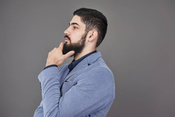 istock Portrait of freelancer man with beard in jacket standing against gray backdrop 955800216