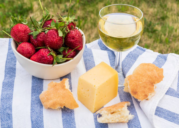 Outdoor spring picnic with strawberry, cheese, bread and glass of wine.