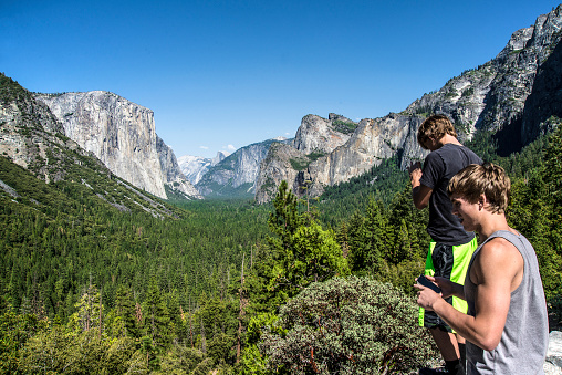 Teenage boys taking photos with their phone in Yosemite Valley. Sierra Nevada, California.